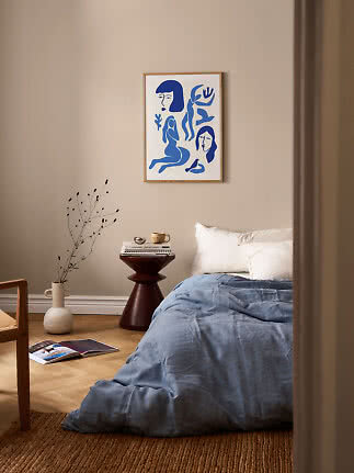 Bedroom with blue bedding and framed abstract blue art print on a beige wall