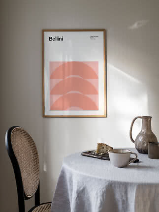 Gerahmtes Bellini-Poster mit rosa Bögen über Tisch mit Tasse, Krug und Kuchen