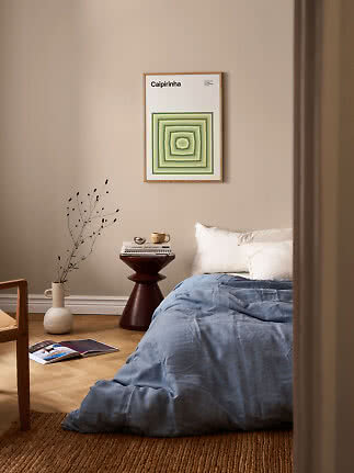Gerahmtes Poster mit grünem geometrischem Muster über einem Bett in beigem Schlafzimmer