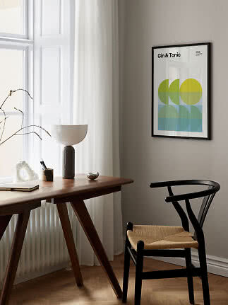 Gerahmtes Gin-&-Tonic-Poster an der Wand über Holztisch und schwarzem Stuhl
