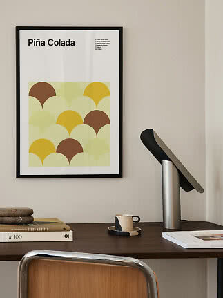 Gerahmtes Piña-Colada-Poster mit gelben und braunen Halbkreisen über einem Schreibtisch