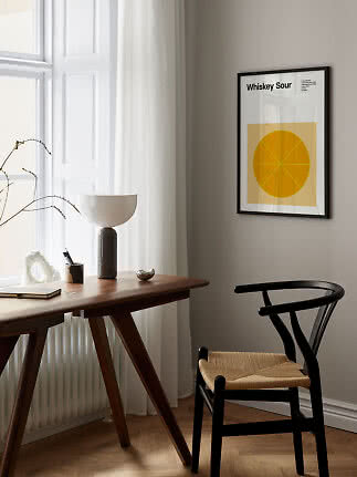 Gerahmtes Whiskey-Sour-Poster mit gelbem Zitrusmotiv an der Wand über Schreibtisch und schwarzem Stuhl