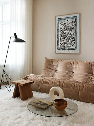 Cozy living room with beige sofa, black floor lamp, glass table and framed wall art