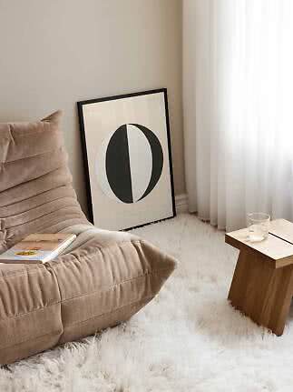 Angolo accogliente con poltrona beige, stampa astratta bianco e nero e tavolino in legno