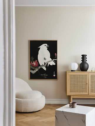 Affiche encadrée d’un cacatoès blanc sur une branche, fond noir, dans un salon moderne