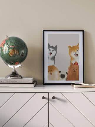 Poster incorniciato con cani su una credenza accanto a un mappamondo e libri