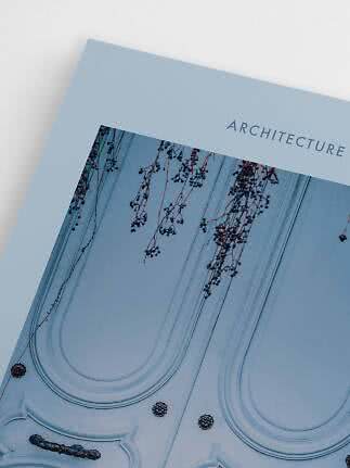 Nahaufnahme eines Buchs oder Posters mit ARCHITECTURE und Foto einer verzierten Fassade mit Zweigen