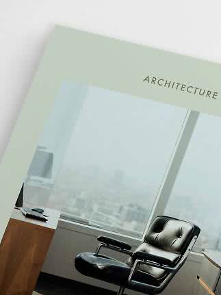 Plakat med teksten "Architecture" foran et moderne kontor med skrivebord og sort lænestol
