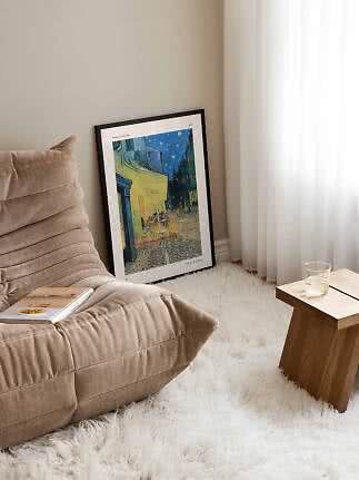 Gerahmtes Van-Gogh-Poster an der Wand neben beigem Sessel, weißem Teppich und Holztisch
