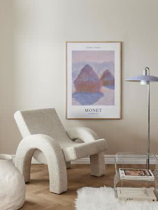 Monet poster in a light wood frame above a cream armchair in a minimalist living room