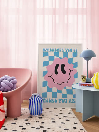 Colorful interior with pink chair, blue striped vase, blue table lamp and graphic poster by pink curtains