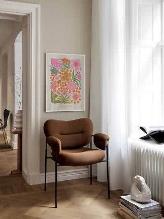 Brun polstret stol ved siden af et farverigt blomsterprint i en lys stue
