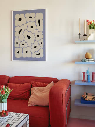 Woonkamer met rode bank en abstracte bloemenposter aan de muur
