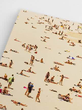 Plakat med luftfoto af solbadende mennesker spredt ud på en stor sandstrand