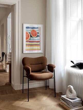 Fauteuil brun près d’une fenêtre avec affiche encadrée de pastèque sur mur beige