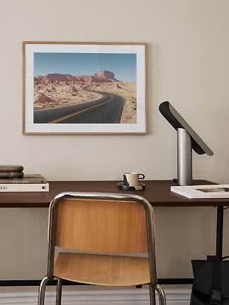 Bureau met stoel, lamp en ingelijste woestijnfoto aan de muur