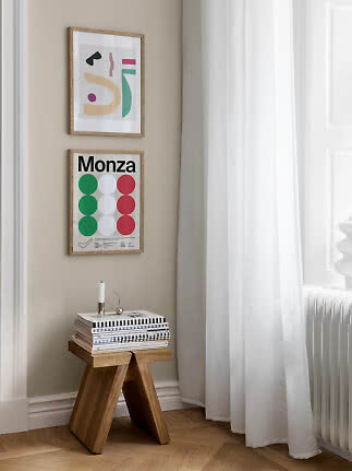Coin lumineux avec deux affiches encadrées au-dessus d’un tabouret en bois avec magazines et bougeoir