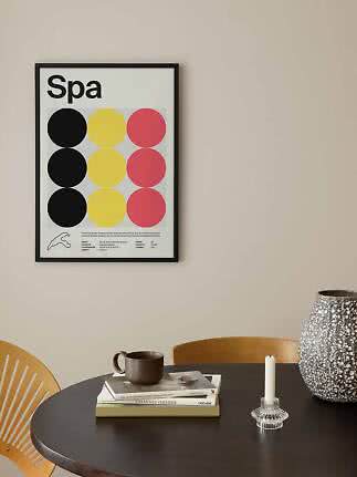 Framed Spa poster with colored circles above a round black table with vase, candle and books