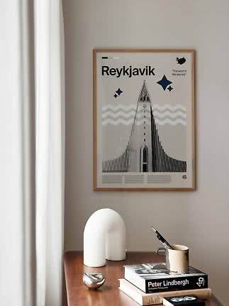 Gerahmtes Reykjavik-Poster mit grafischer Kirchenillustration an beiger Wand über Holztisch