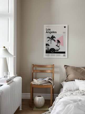 Los Angeles-plakat i hvid ramme over træstol ved seng i lyst soveværelse