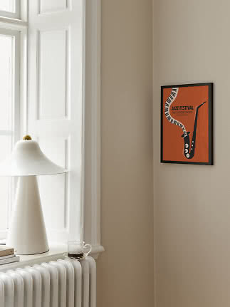 Affiche orange encadrée de festival de jazz avec saxophone sur mur beige près d'une fenêtre