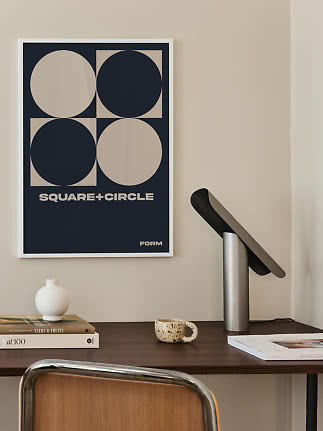 Poster grafico incorniciato con quadrati e cerchi blu scuro e beige sopra una scrivania