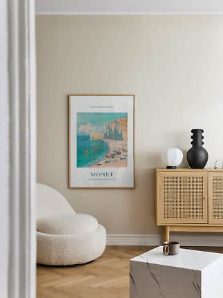 Monet framed poster on a beige wall above a light wood cabinet with cane doors
