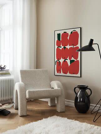 Mysig hörna med boucléfåtölj, svart golvlampa och poster med röda paprikor på beige vägg