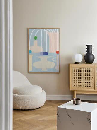 Abstract framed poster on a beige wall above a white armchair in a modern living room