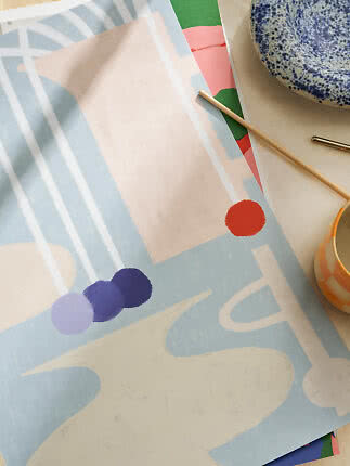 Abstract art print in light blue, cream and coral on table with ceramic bowl and mug