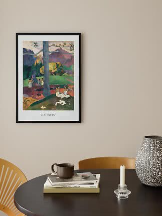 Gerahmtes Gauguin-Poster mit farbiger Landschaft über einem dunklen Tisch mit Vase und Kerzenhalter.