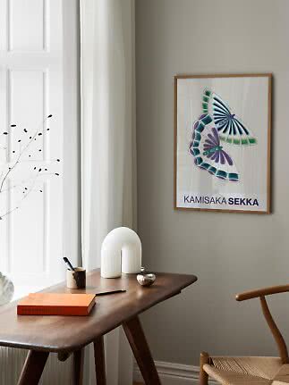Gerahmter Kunstdruck mit bunten Schmetterlingen über einem Holztisch am Fenster
