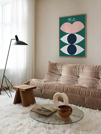 Modernt vardagsrum med beige soffa, svart golvlampa och färgstark abstrakt poster på väggen