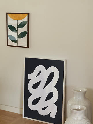 To moderne plakater ved en beige væg, en botanisk på væggen og en abstrakt på gulvet ved hvide vaser