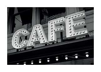 Schwarzweißfoto eines beleuchteten Café-Schilds mit Glühbirnen an einer Fassade