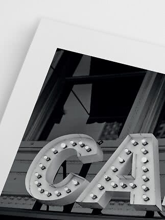 Schwarz-Weiß-Foto eines beleuchteten Ladenschilds mit den Buchstaben C und A am Fenster