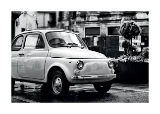 Black-and-white photo of a small vintage car parked on a wet street
