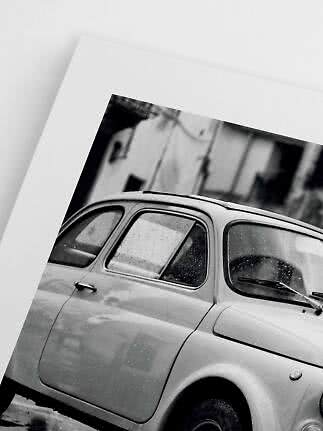 Black-and-white print of a classic small car photographed close up in the rain