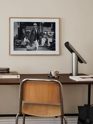 Desk with chair, lamp and framed black-and-white photo on a beige wall
