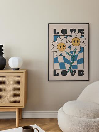 Inramad poster med två leende blommor och texten LOVE på en beige vägg