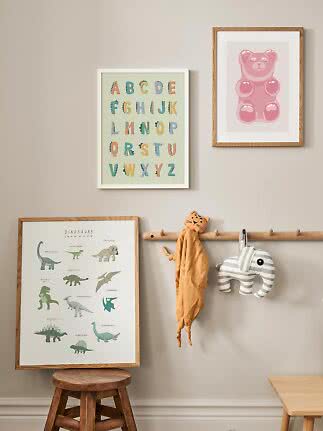Children’s room wall with framed prints, wooden rack, and soft tiger and elephant toys