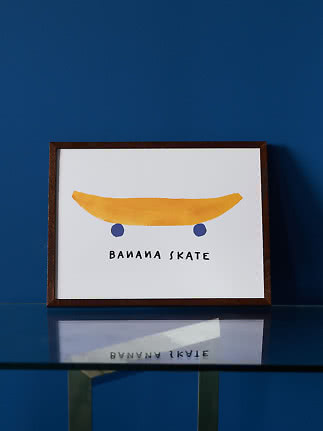 Framed print of a yellow banana as a skateboard with the text "Banana Skate"