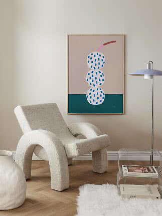 Modern living room with cream lounge chair and framed poster of three spotted spheres on the wall