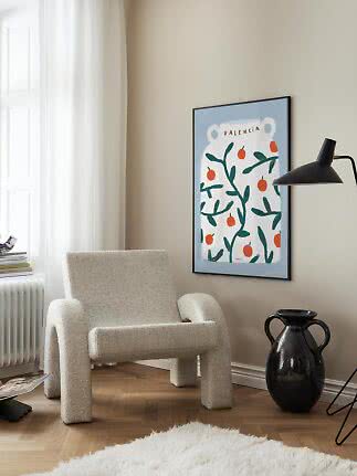 Gerahmtes Valencia-Poster mit Orangenmotiv an beigefarbener Wand über einem Sessel
