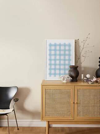 Lyst træskab med fletlåger, vase med grene og blåternet plakat mod beige væg