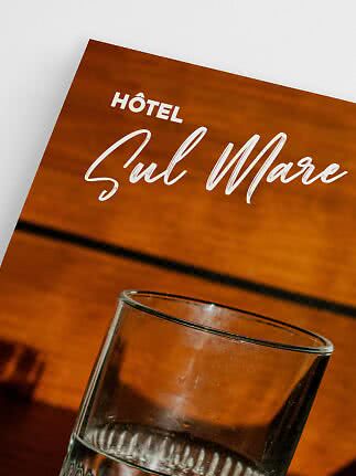 Glas med vand foran et orange skilt med teksten "Hôtel Sul Mare"