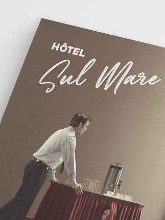 Mand læner sig over serveringsbord med kaffe og kopper under skiltet Hôtel Sul Mare.