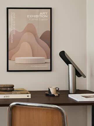 Ingelijste kunstposter met zachte, golvende vormen in beige en roze aan de muur boven een bureau