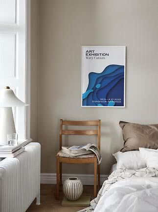 Blue abstract art poster in a white frame above a wooden chair beside a bed