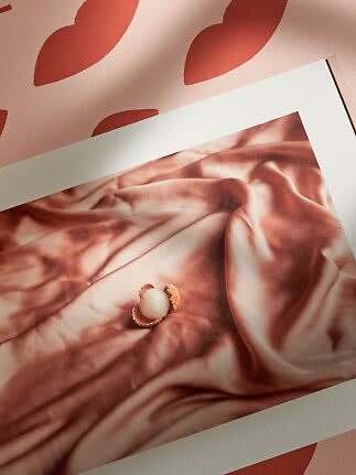 Plakat med rosa silkestof og en lille åben nød på mønstret lyserød baggrund